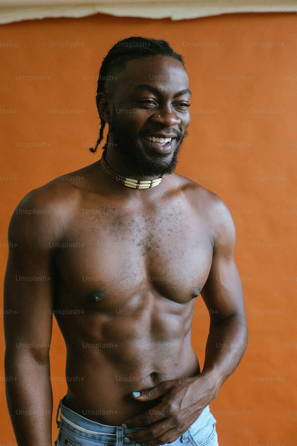 a shirtless man wearing a choker and jeans