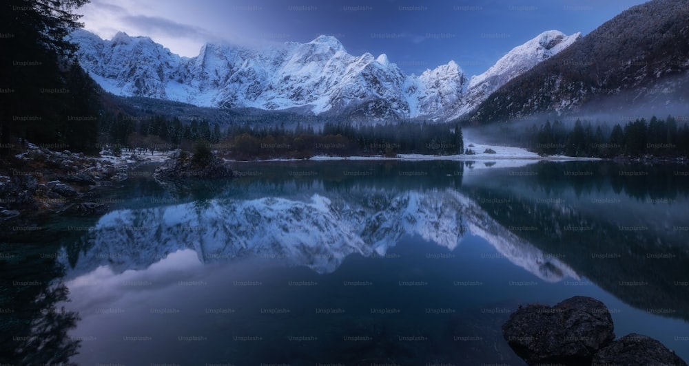 un lac entouré de montagnes enneigées sous un ciel nuageux