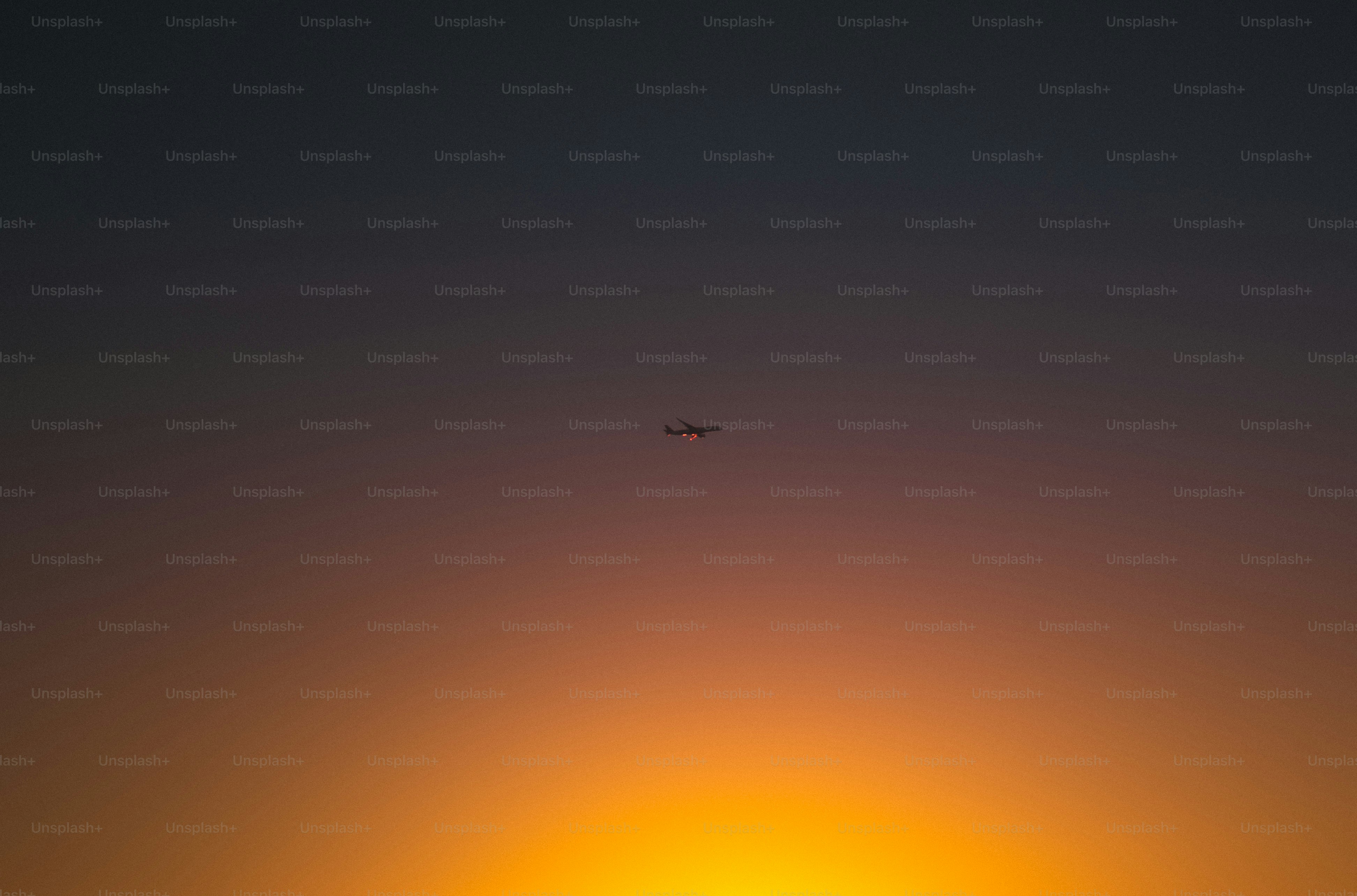 a plane flying in the sky at sunset
