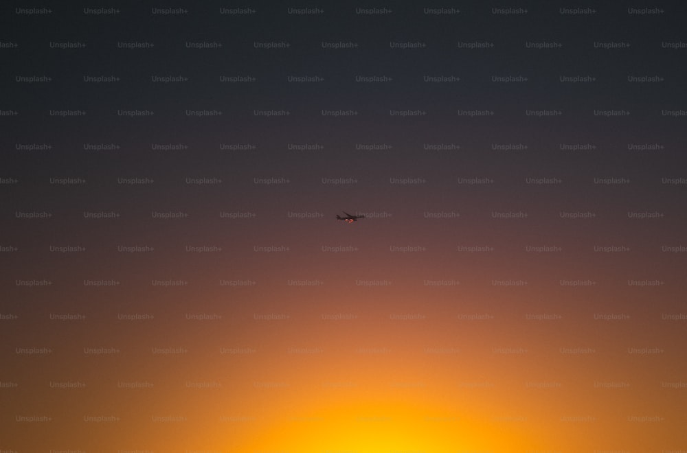 um avião voando no céu ao pôr do sol