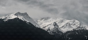 a snow covered mountain range under a cloudy sky