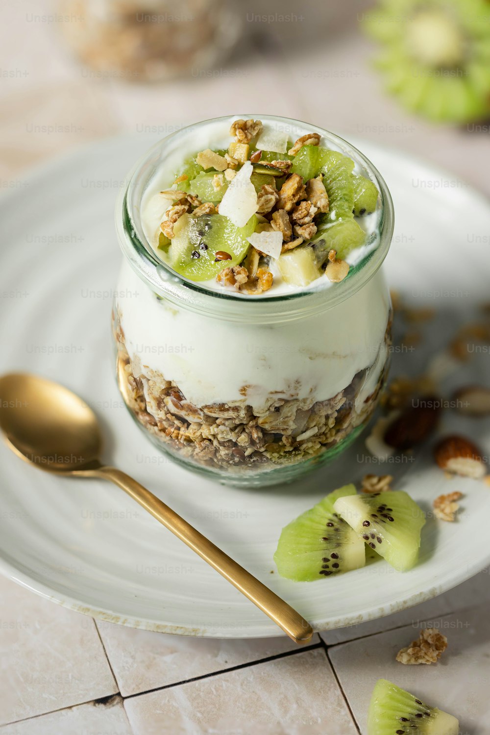 a dessert in a glass jar with kiwis and nuts