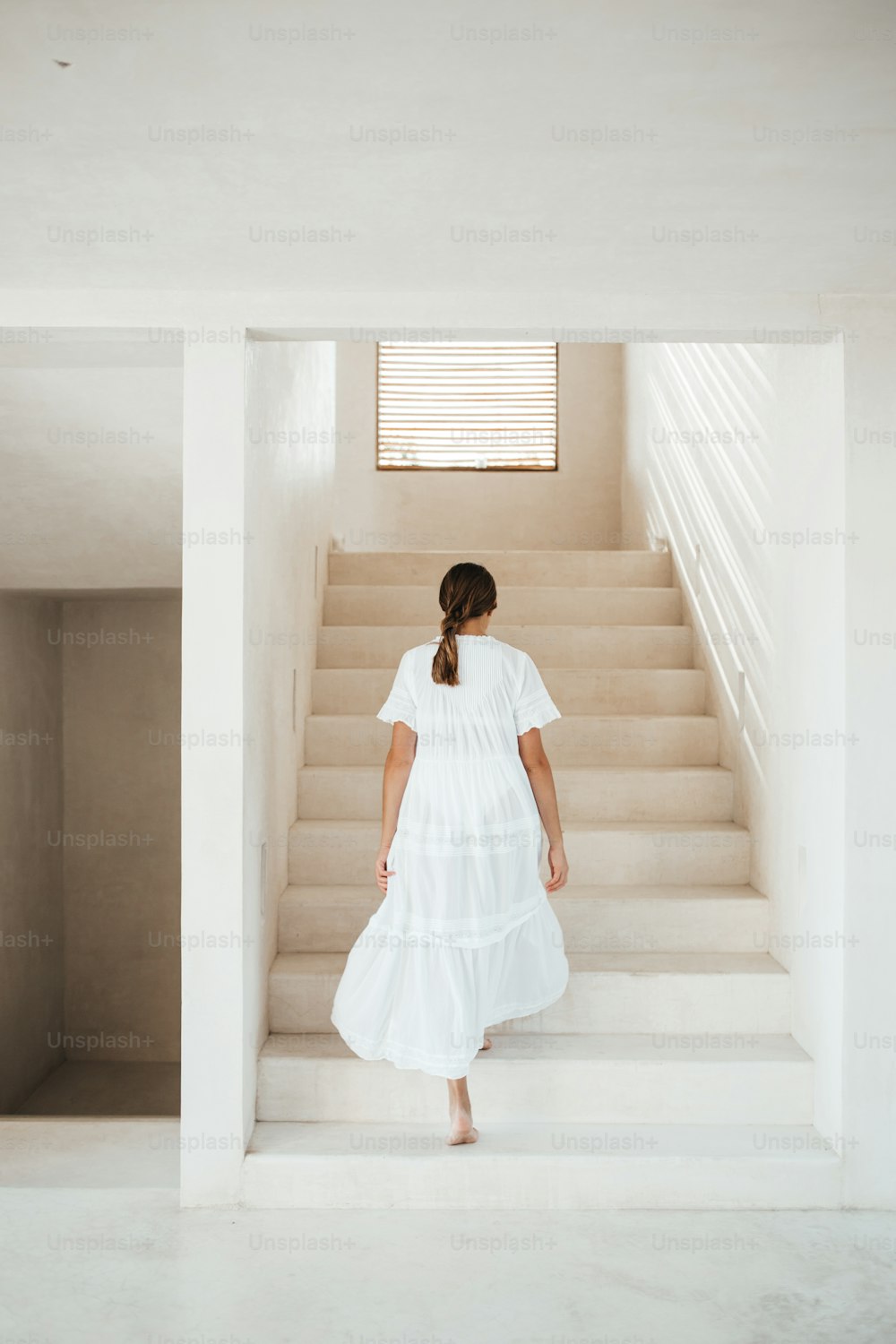 Una mujer con un vestido blanco subiendo un tramo de escaleras
