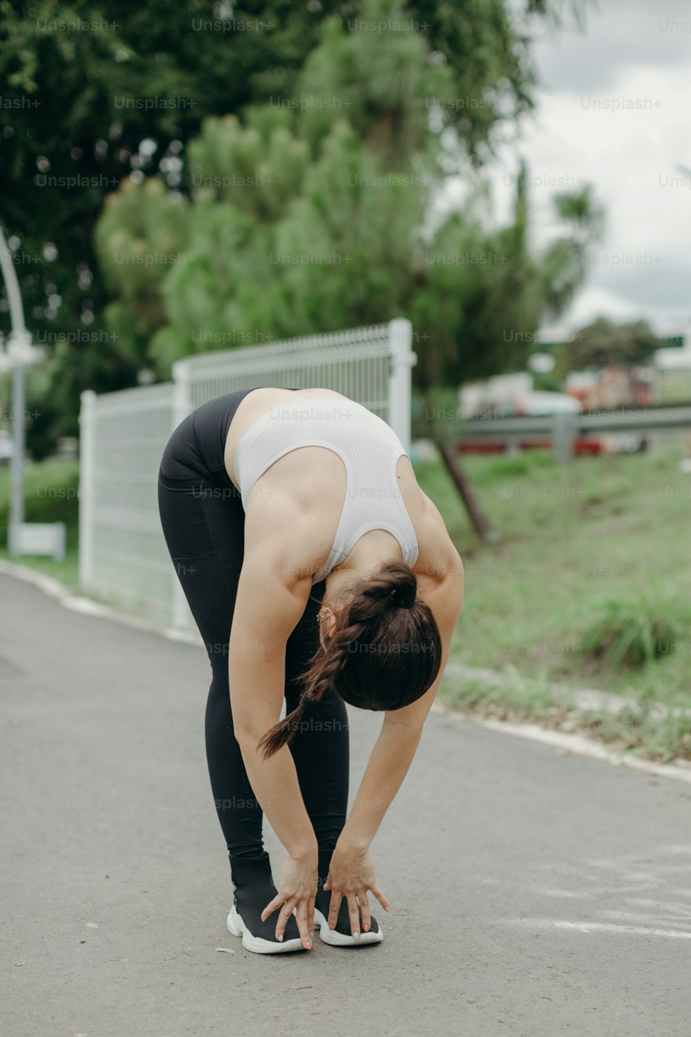 a woman in a white tank top and black leggings doing a yoga pose