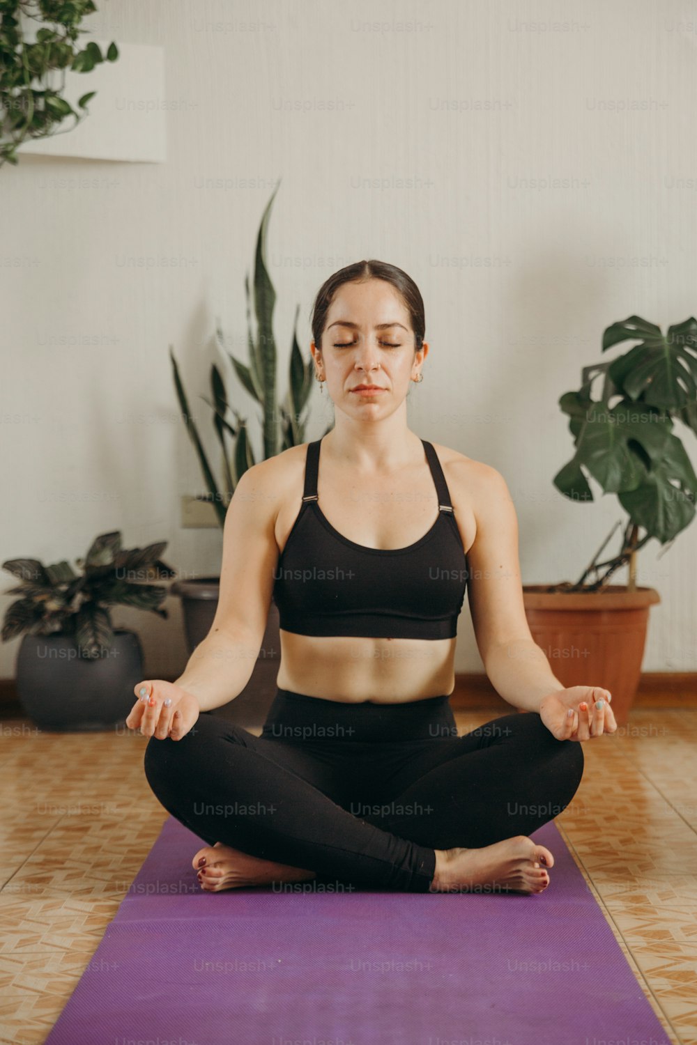 Una donna seduta in posizione yoga con gli occhi chiusi