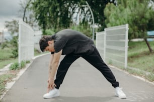 a man stretching his legs on a paved road