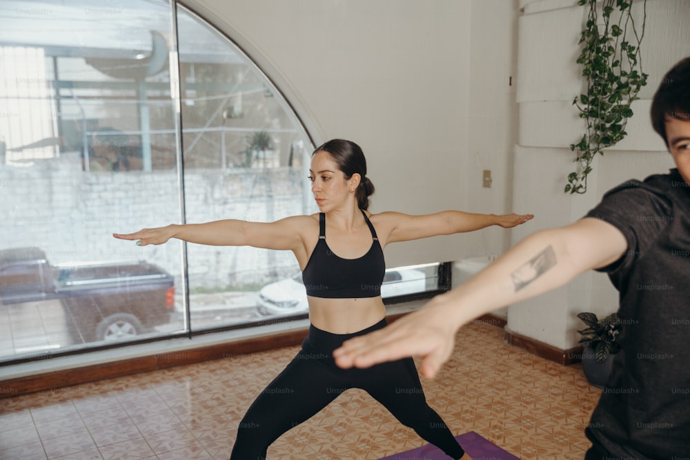 a man and a woman doing yoga in front of a window
