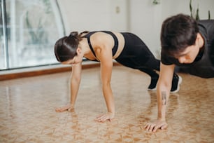 a man and a woman doing push ups on the floor