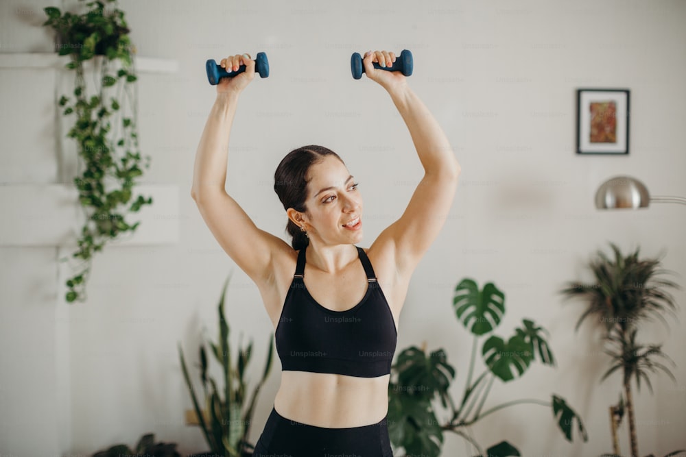 a woman in a black sports bra holding two dumbbells