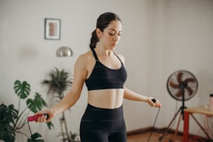 a woman in a black sports bra top and black leggings holds a red