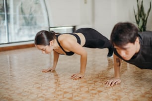 a man and a woman doing push ups on the floor