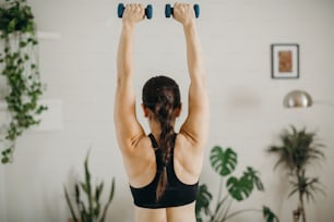 a woman is doing exercises with two dumbbells