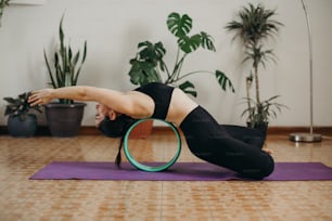 a woman doing a yoga pose with a hoop