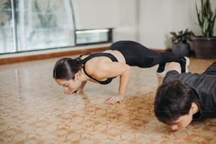 a man and a woman doing push ups on the floor
