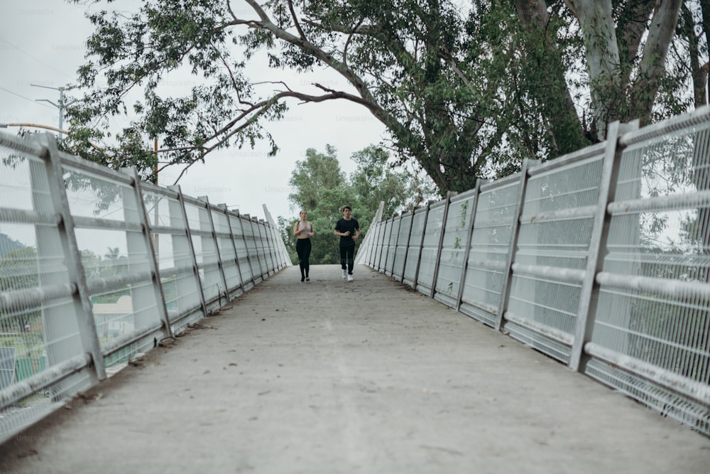 a couple of people walking across a bridge