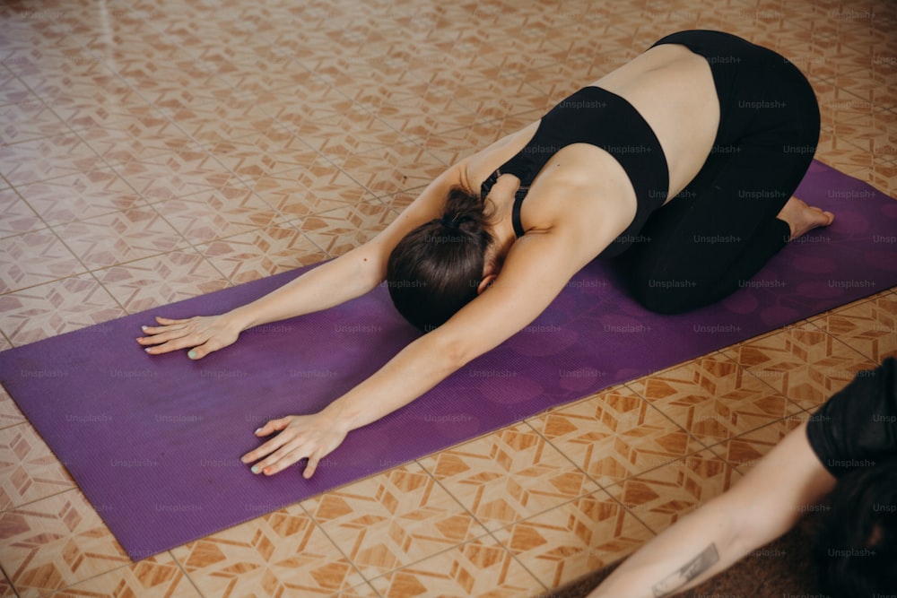 uma mulher está fazendo uma pose de yoga em um tapete