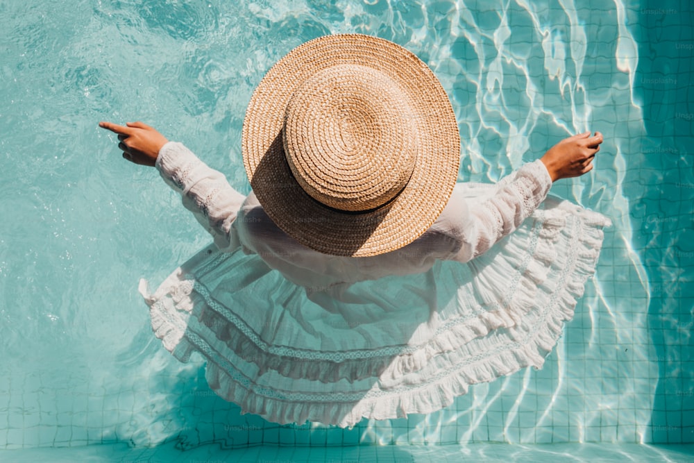 Una mujer con un sombrero de paja parada en una piscina