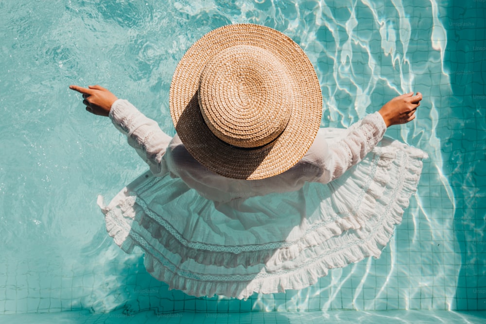 a woman in a straw hat standing in a pool