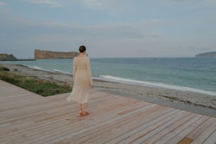 Una mujer parada en una cubierta de madera cerca del océano