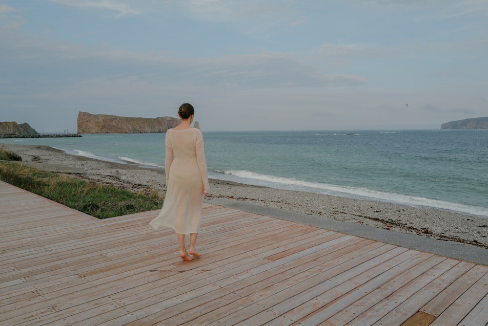 uma mulher em pé em um deck de madeira perto do oceano