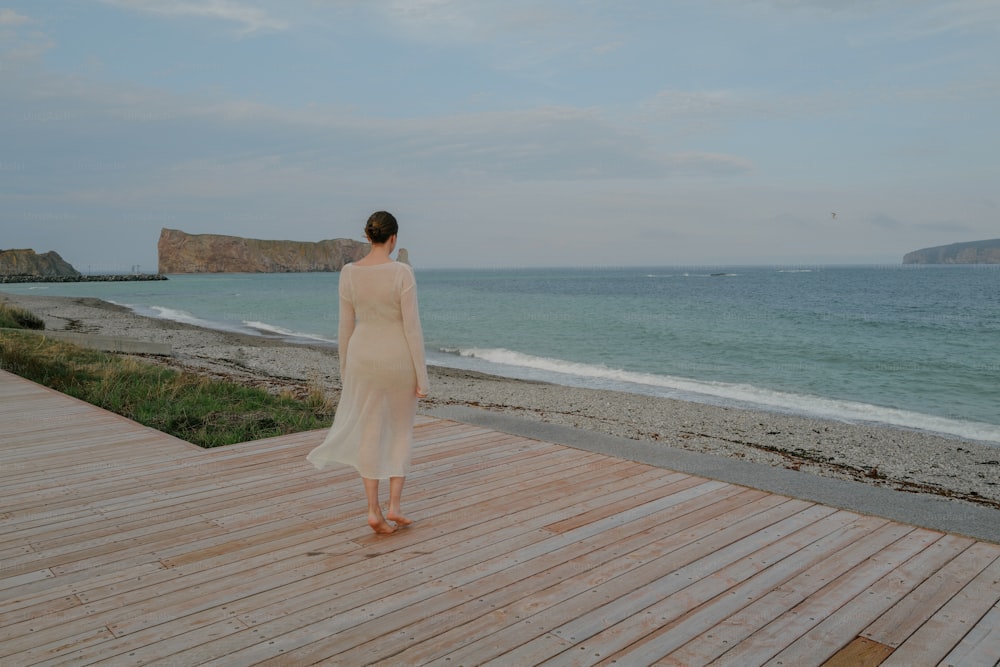 a woman standing on a wooden deck near the ocean