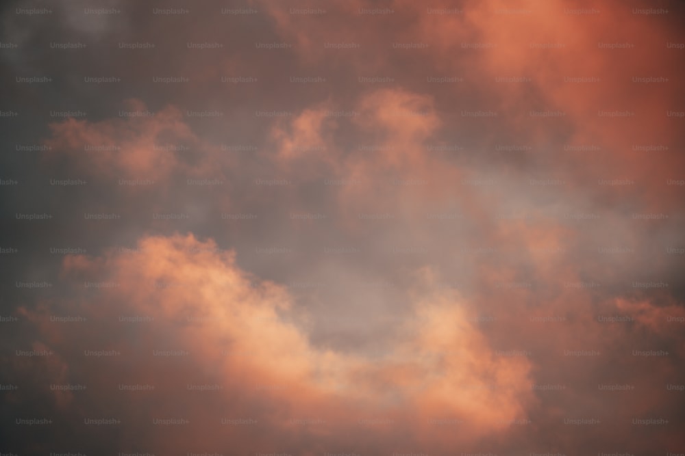 a plane flying through a cloudy sky at sunset