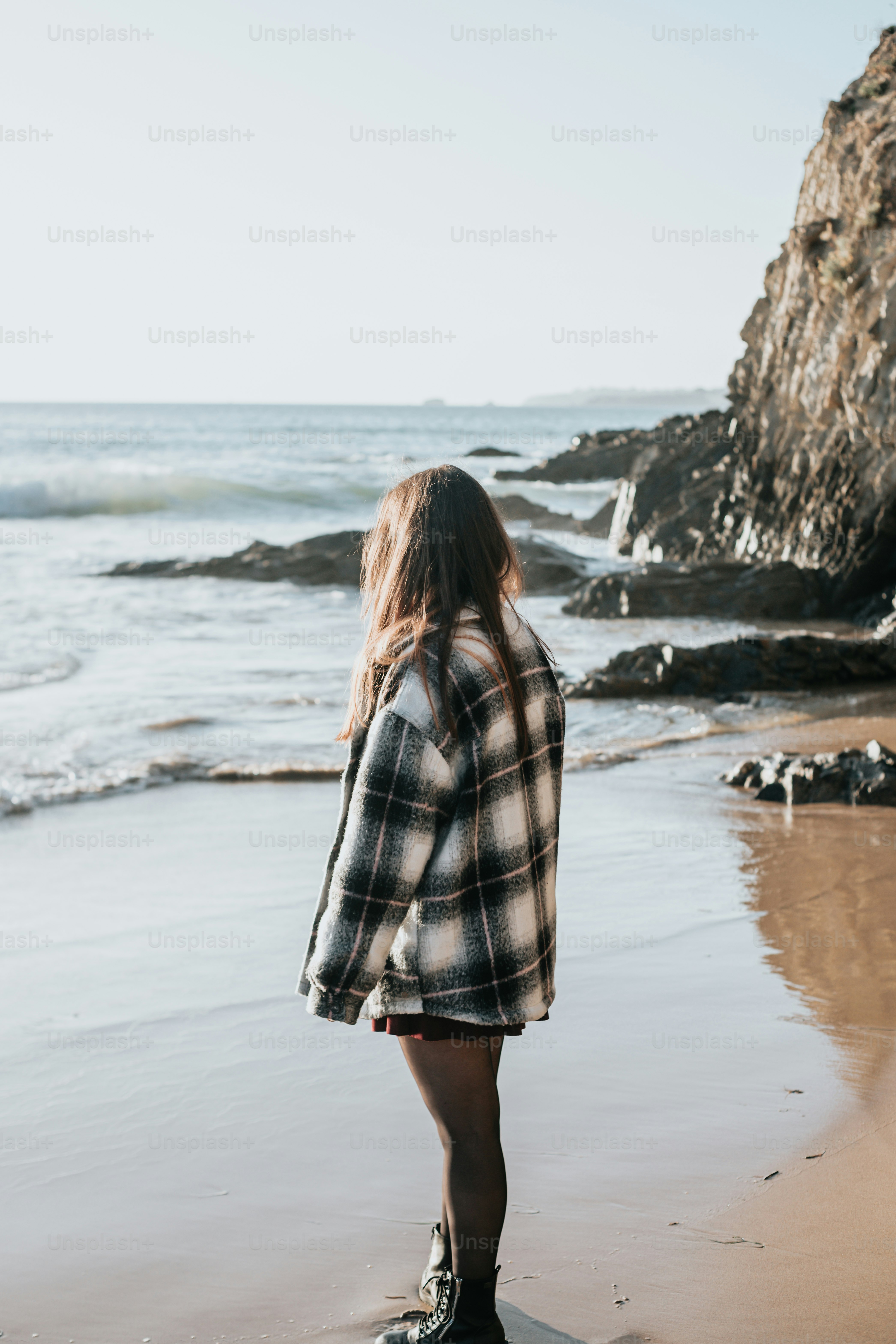 a woman standing on a beach next to the ocean