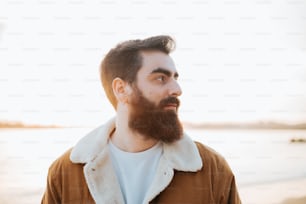 a man with a goatee and a beard standing on a beach