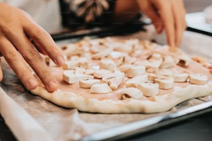 a close up of a person putting toppings on a pizza