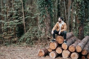 a man sitting on top of a pile of logs
