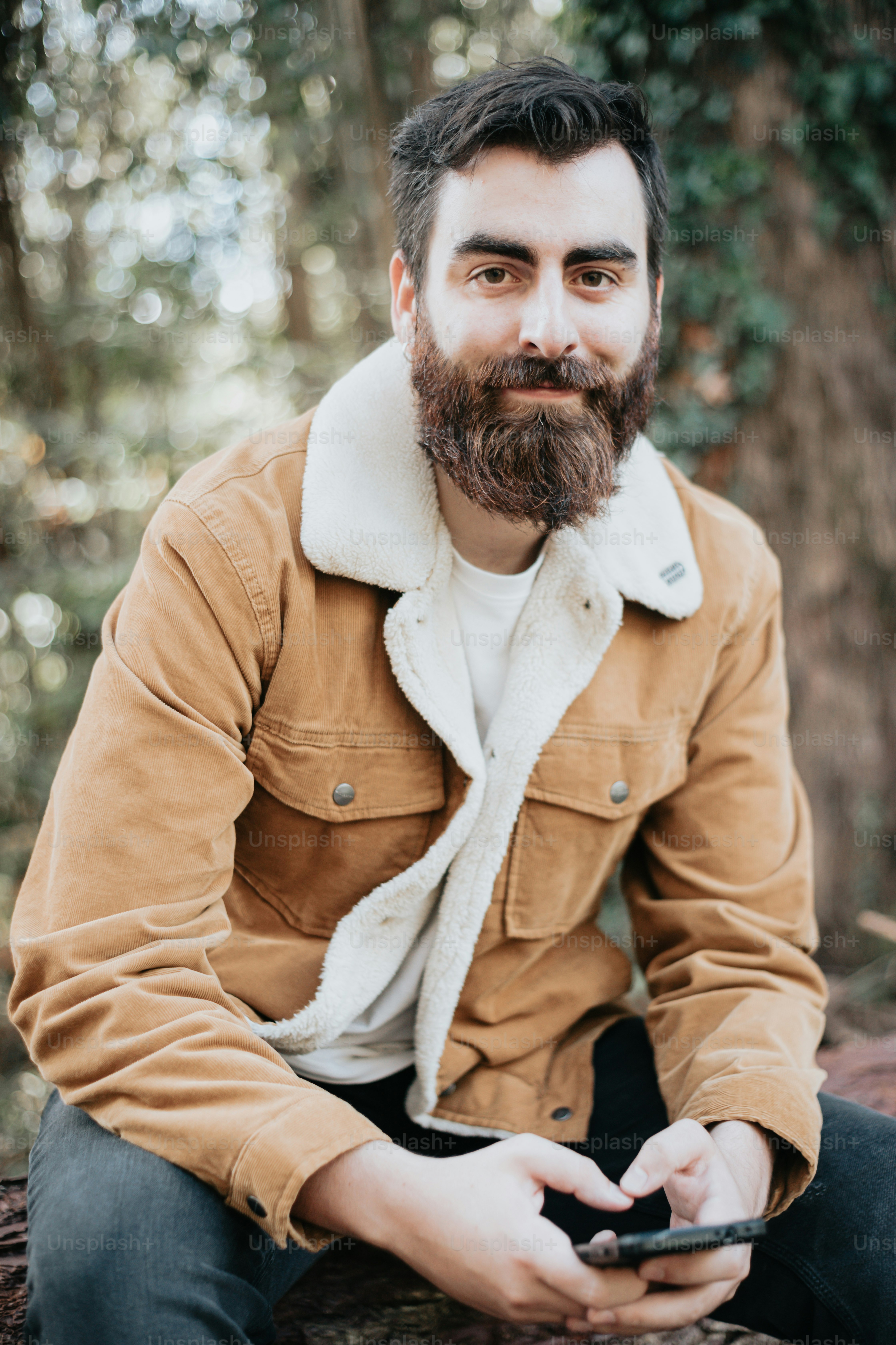 숲 속의 통나무에 앉아 있는 턱수염을 가진 남자