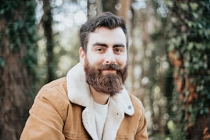 a man with a beard and a jacket in the woods
