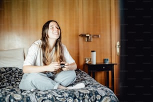 a woman sitting on a bed playing a video game