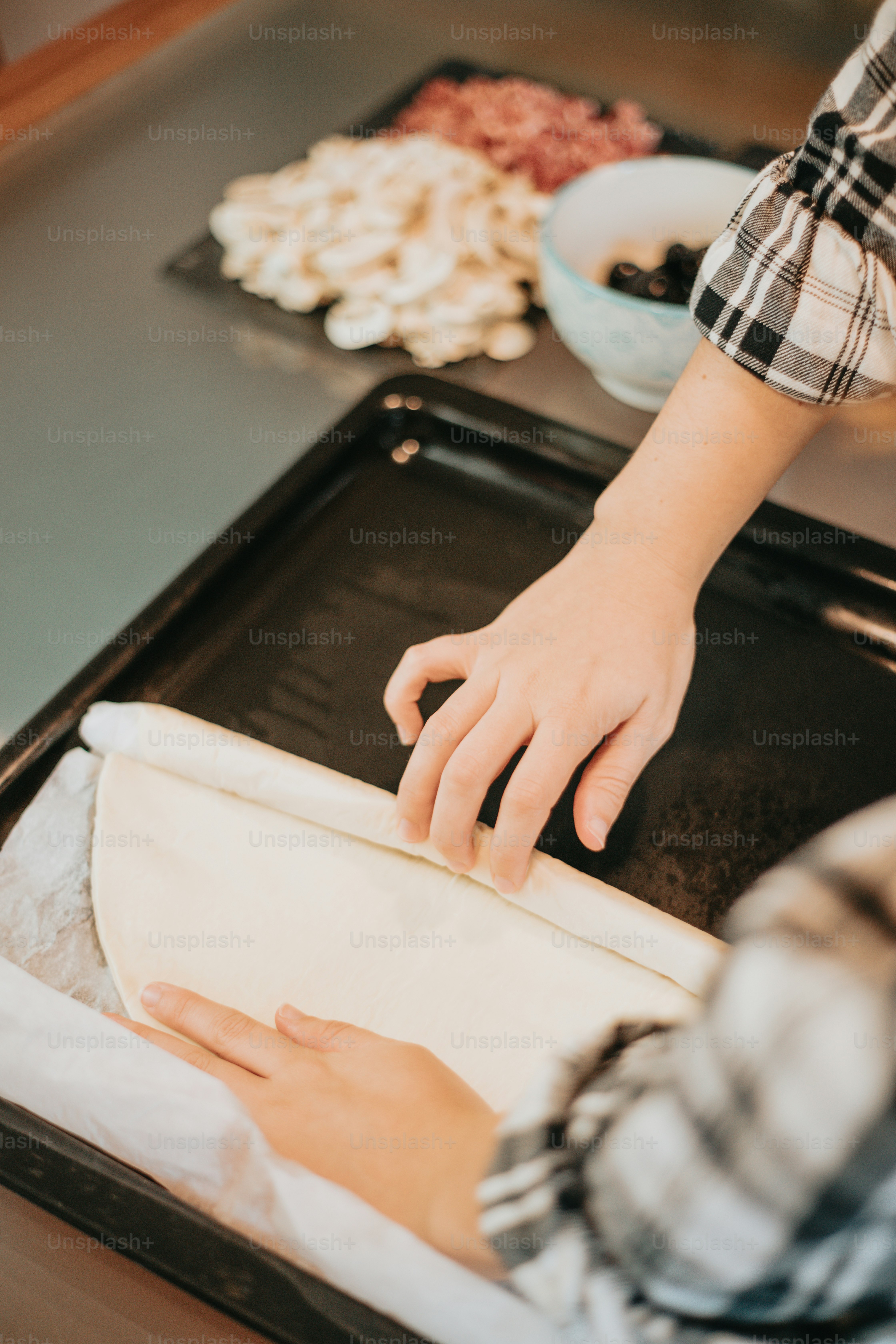 una persona che stende l'impasto su una teglia da forno