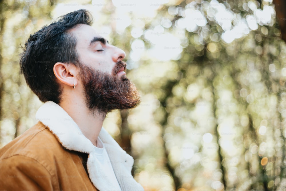 a man with a beard is standing in the woods