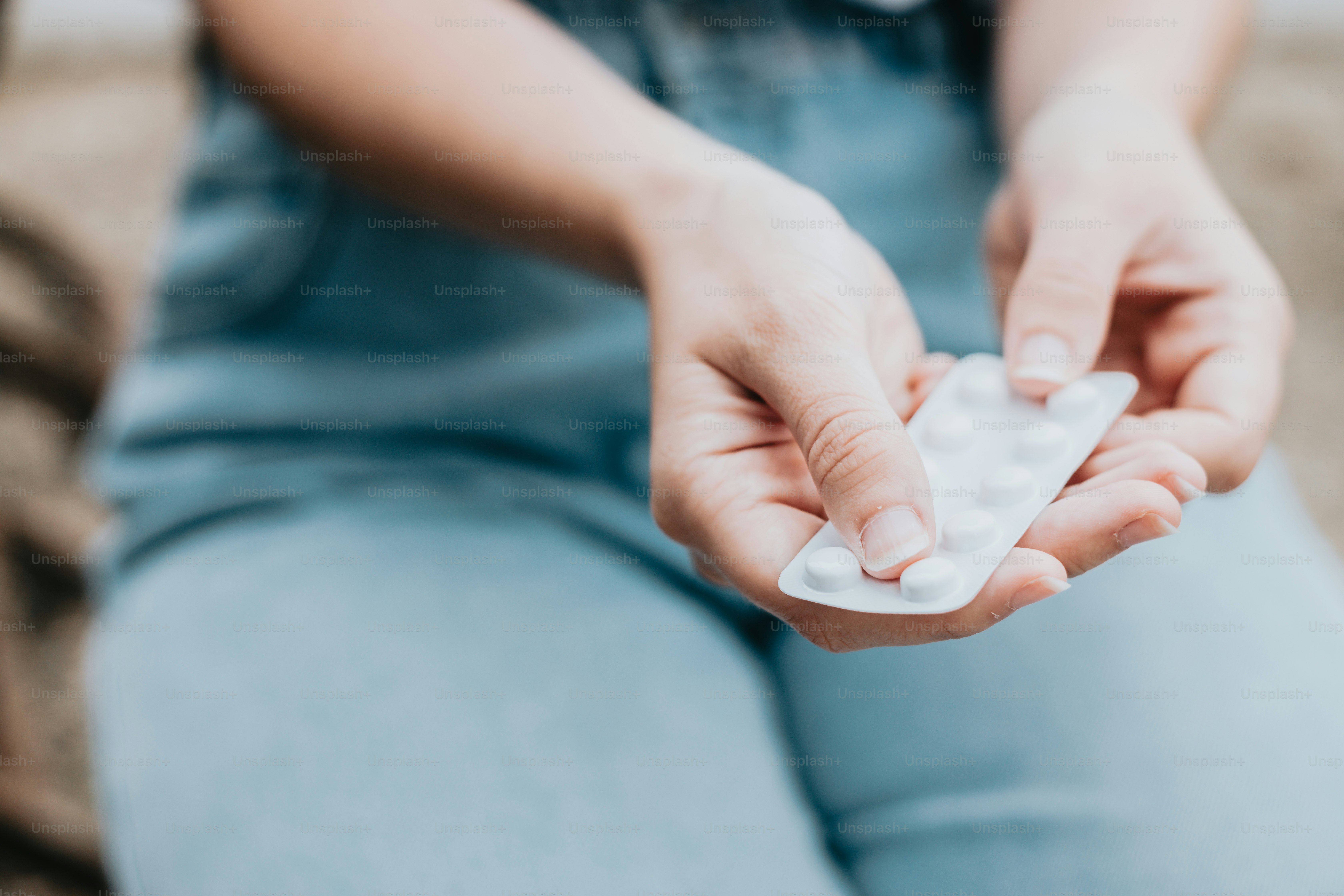 A person sitting on a couch holding a pill bottle photo Drugs Image