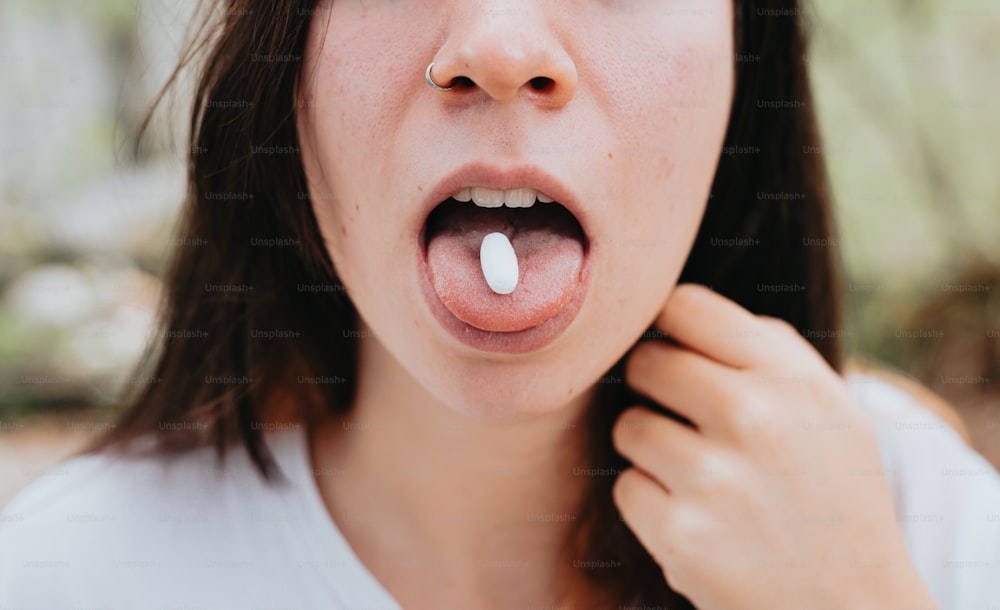 uma mulher segurando uma pílula na boca
