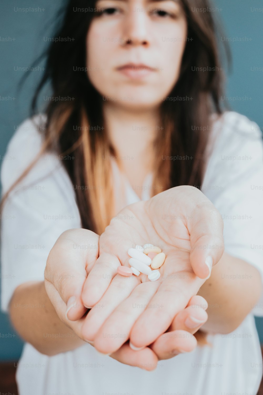 Una mujer sosteniendo un puñado de píldoras en sus manos