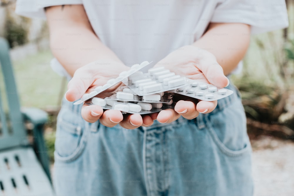 a person holding a bunch of pills in their hands