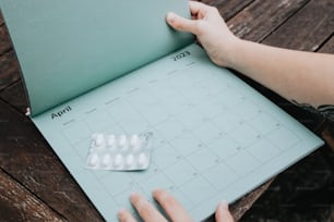 uma pessoa está segurando um calendário com pílulas nele