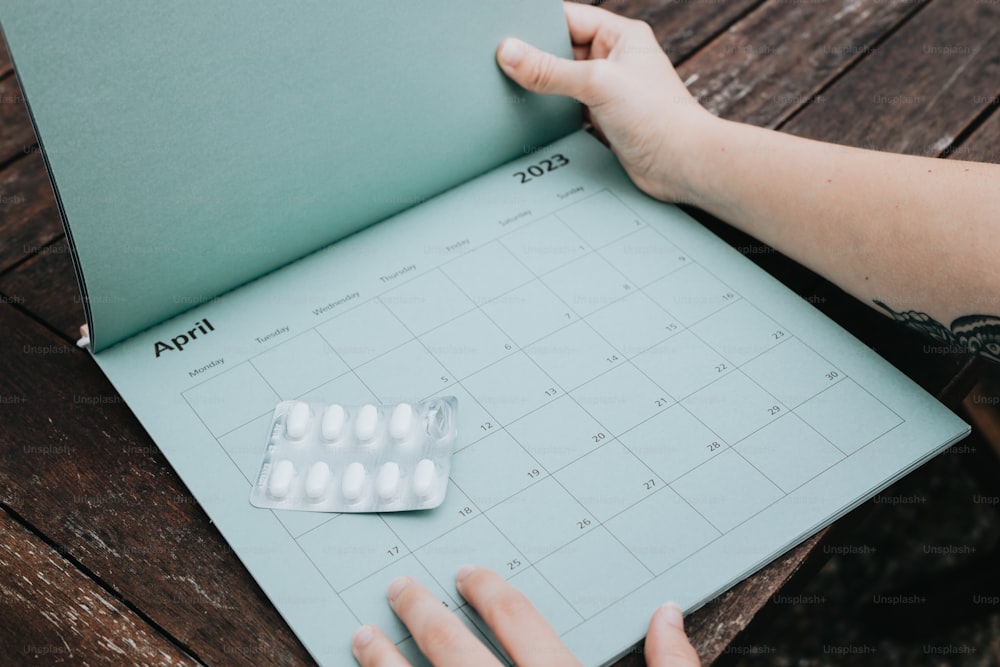 a person is holding a calendar with pills on it
