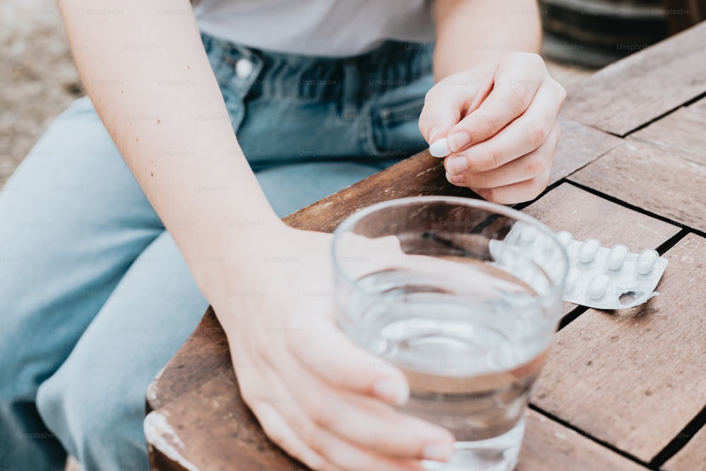 コップ一杯の水を持�ってテーブルに座っている人