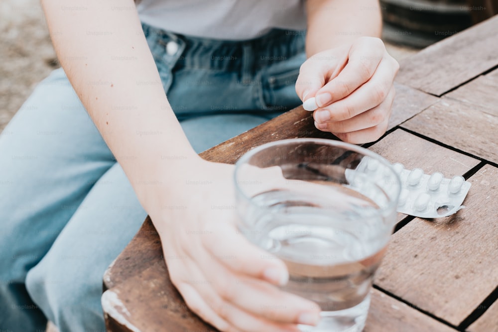 Una persona sentada en una mesa con un vaso de agua