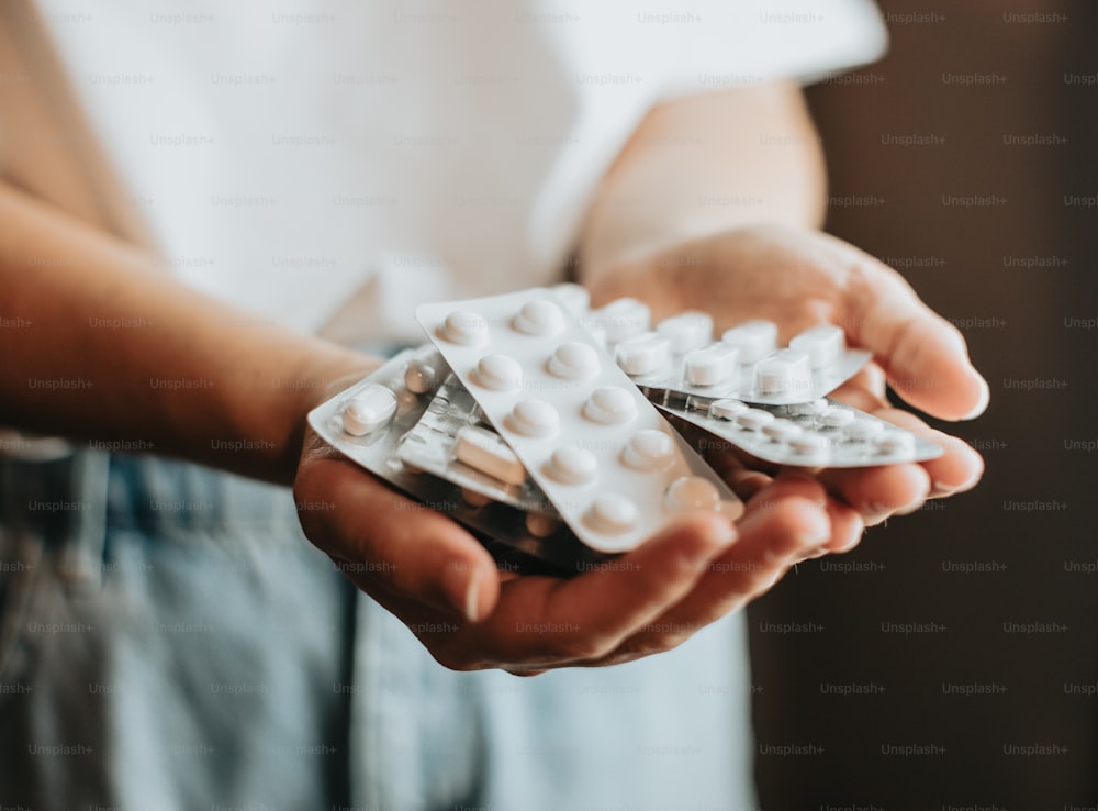 a person holding a bunch of pills in their hands