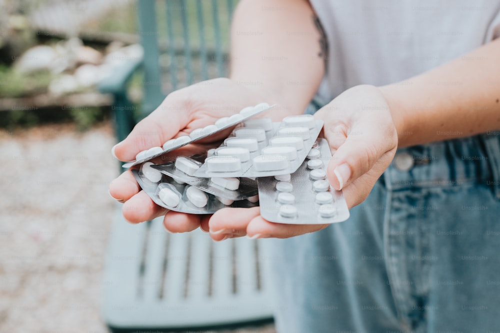 a person holding a bunch of pills in their hands