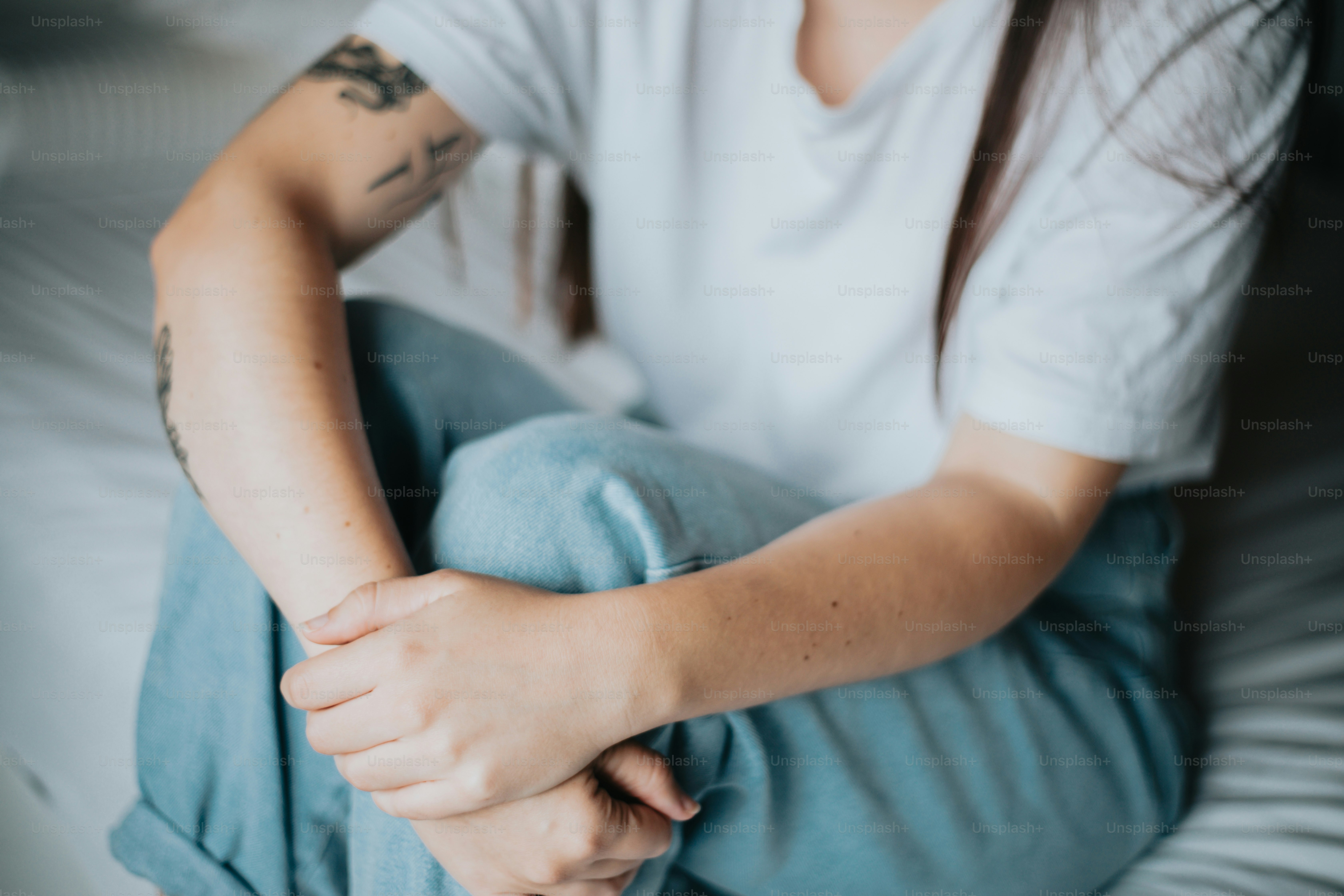 a woman sitting on a bed with her hands on her knees