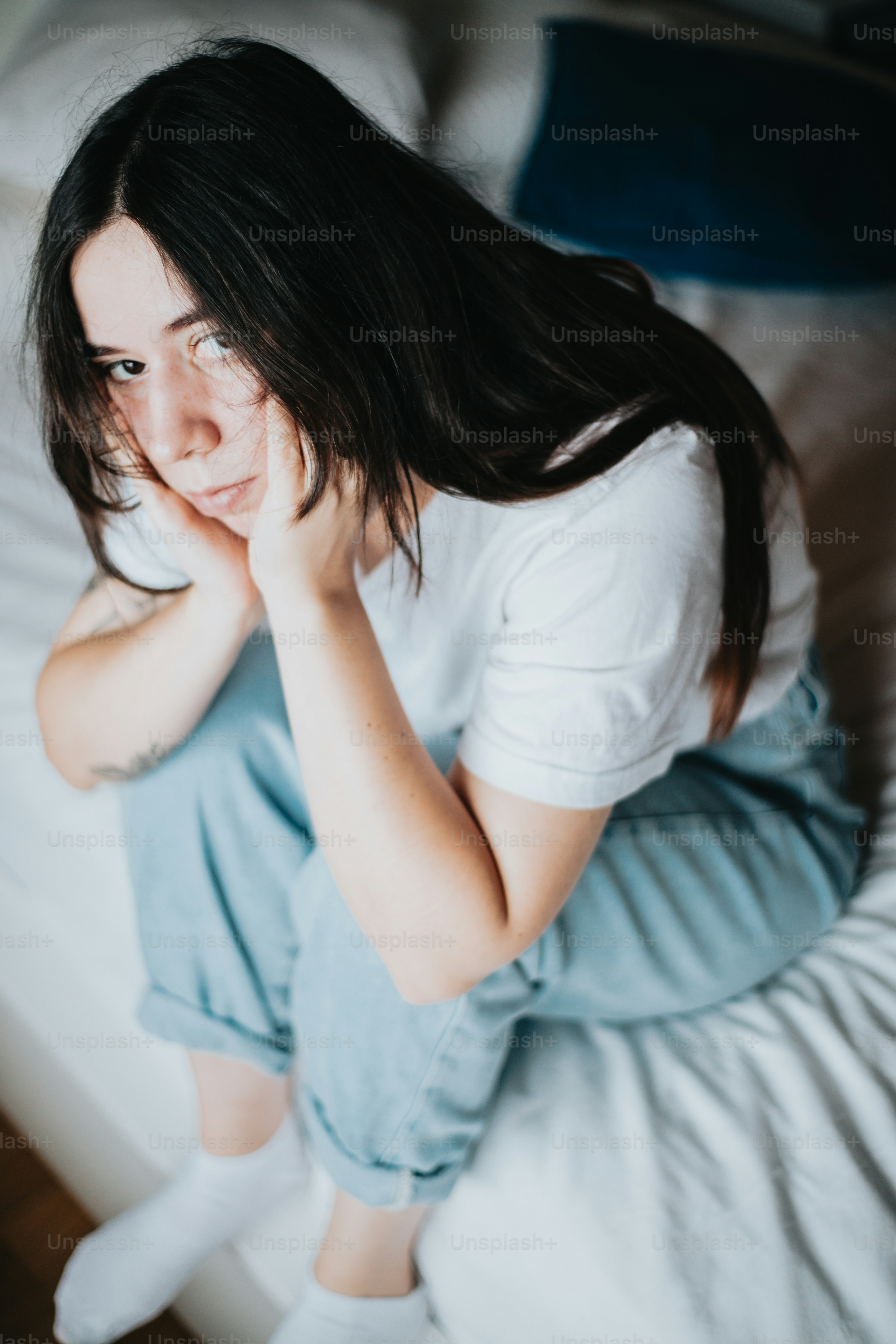 베개 옆 침대 위에 앉아 있는 여자