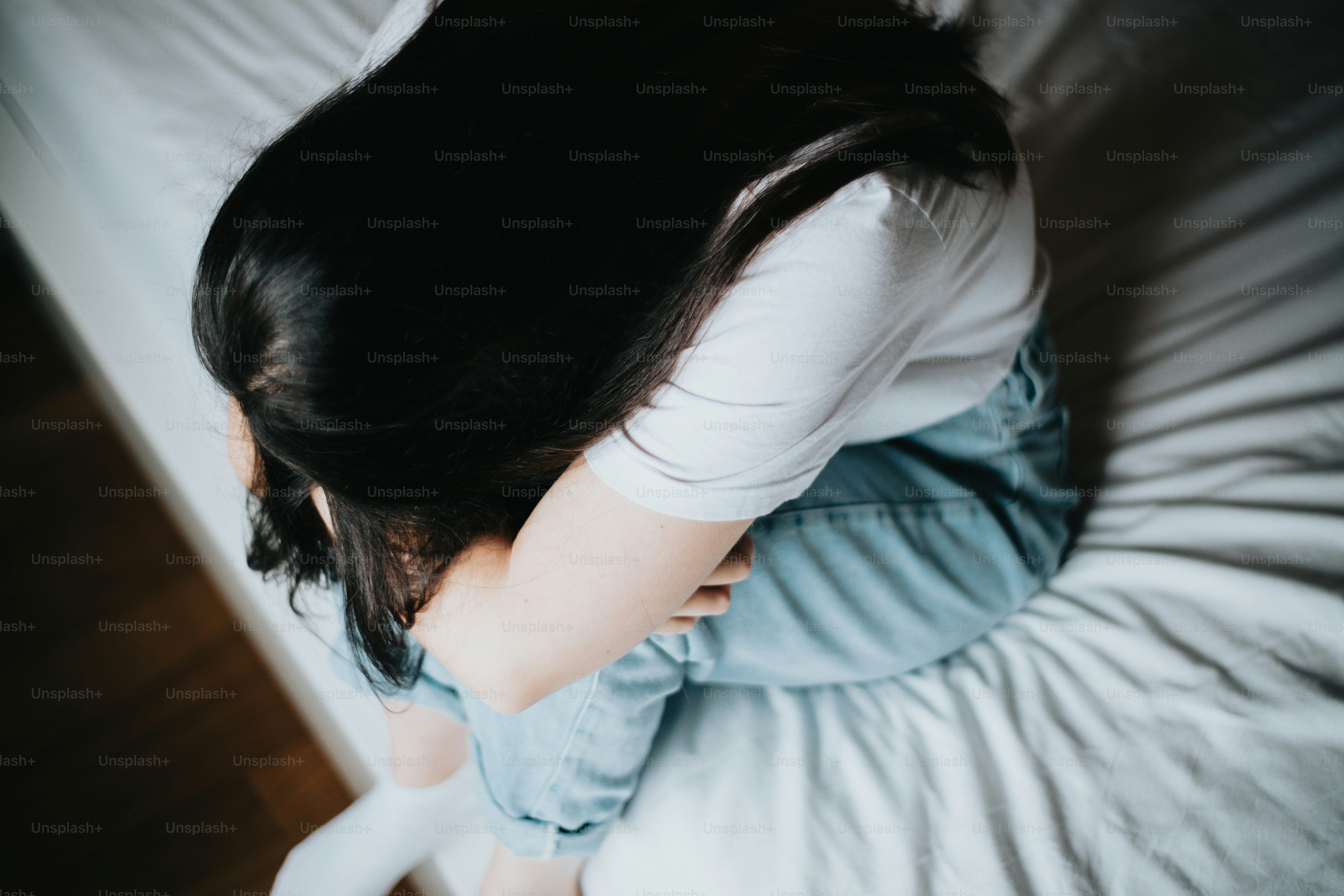 白いベッドの上に座っている女性