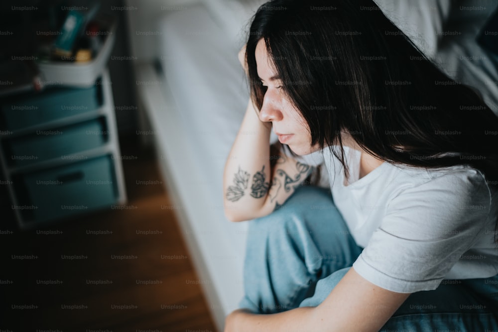 a woman sitting on a bed with a tattoo on her arm