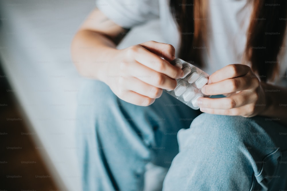 a person sitting on a bed holding something in their hands